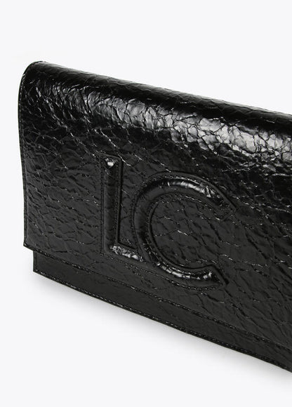 Bandolera Lola Casademunt  con solapa efecto piel brillante con logo en relieve Negro
