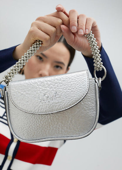 Bandolera Lola Casademunt efecto piel metalizada con asa metálica decorativa plateado